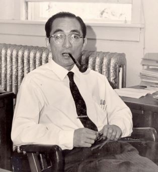 Photo of Yoshi Sasaki, former CIMMS Director, in 1969, sitting at a desk with a pipe in his mouth.