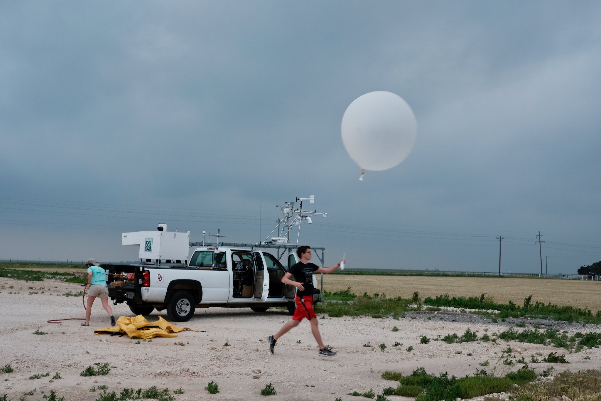 OU CIMMS Research Associate and student Nolan Meister releases a weather balloon with instruments attached to measure aspects of the upper atmosphere. (Photo by Mike Coniglio/NOAA NSSL) | The TORUS Windsond team from the University of Oklahoma Cooperative Institute for Mesoscale Meteorological Studies supporting NOAAs National Severe Storms Laboratory. The team is near the hail core of a storm in May 2019. (Photo by Christiaan Patterson