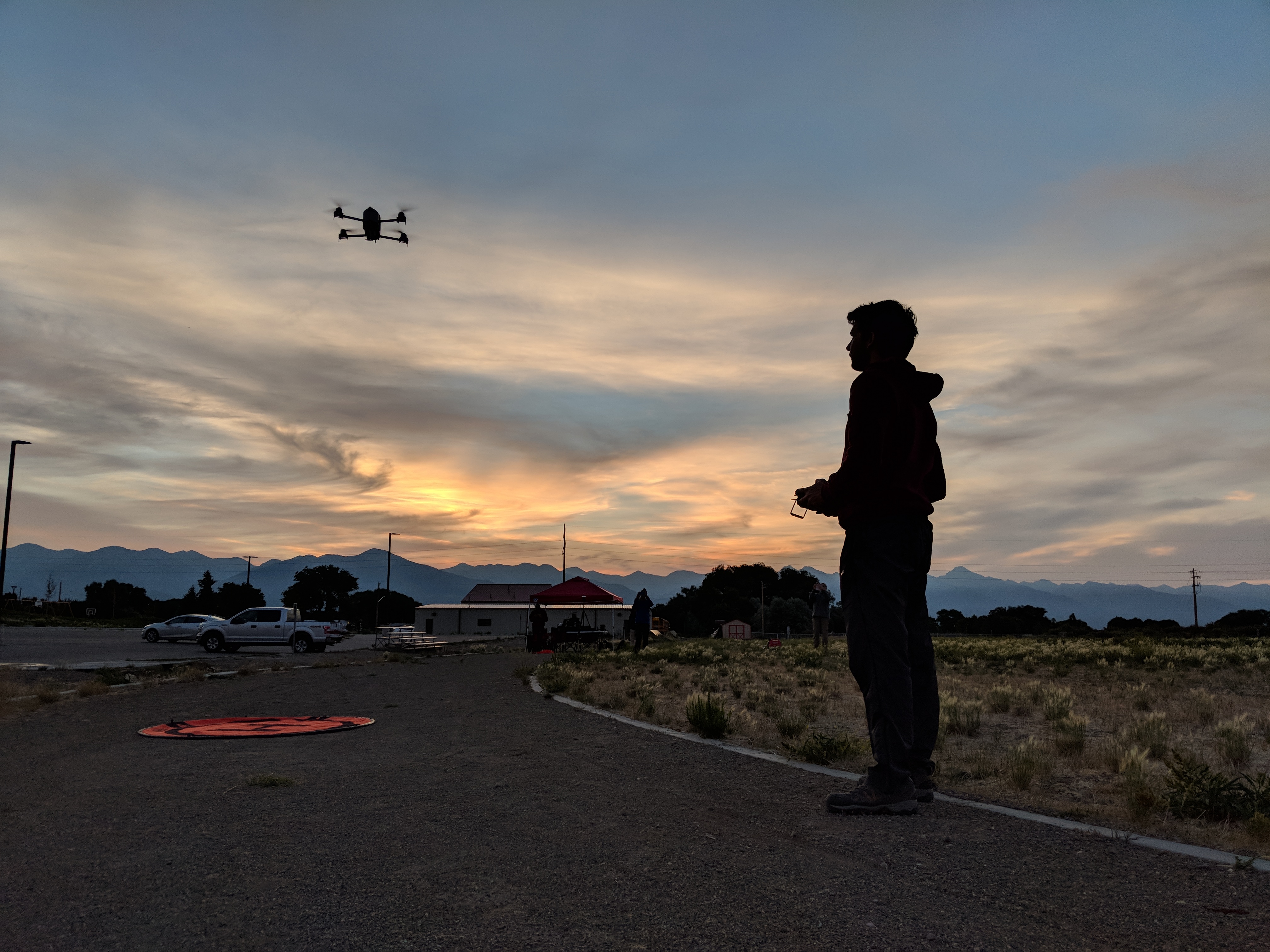 A person flying a drone as the sun sets behind them. | A person holding a Coptersonde UAS. | Two people standing together with a drone.